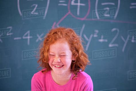 Portrait Of Cute Primary Schoolgirl Giggling In Classroom Stock Photo