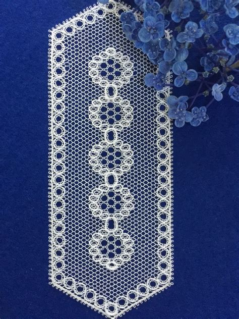 A White Crocheted Tie Next To Some Blue Flowers On A Blue Tablecloth