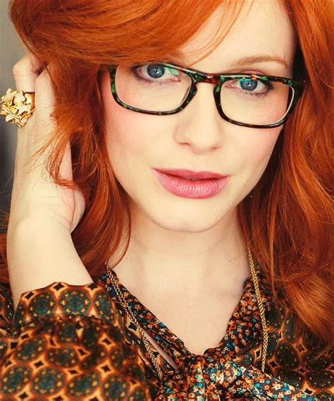 A Close Up Of Christina Hendricks Wearing Glasses She Has Her Right Hand Raised To Her Ear And