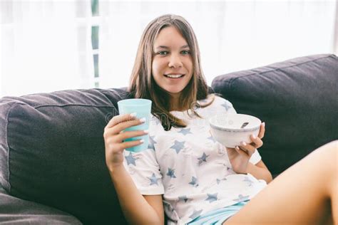 Teenage Girl Eating Brekfast On Couch In Living Room Stock Image