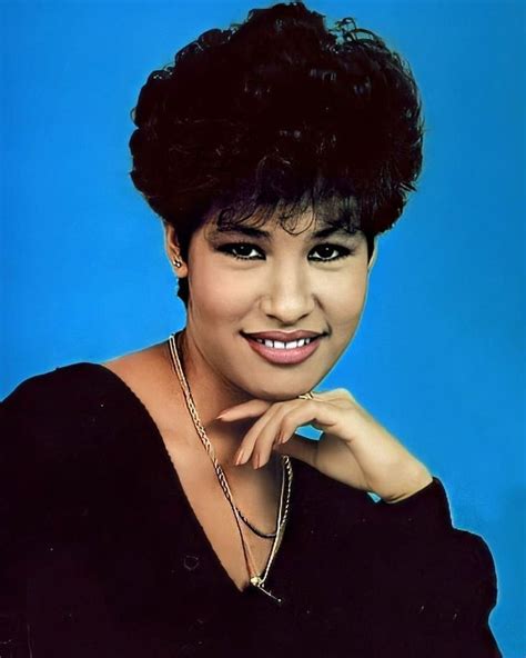 An Old Photo Of A Woman With Short Hair And Wearing A Black Top Smiling