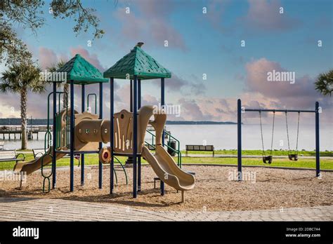 A Colorful Playground With Swings And A Sliding Board In A Park By The