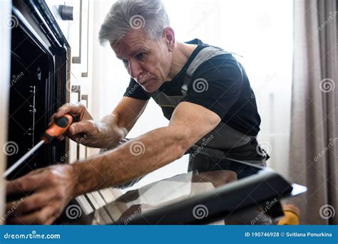 Close Up Shot Of Aged Repairman In Uniform Working Fixing Broken Oven
