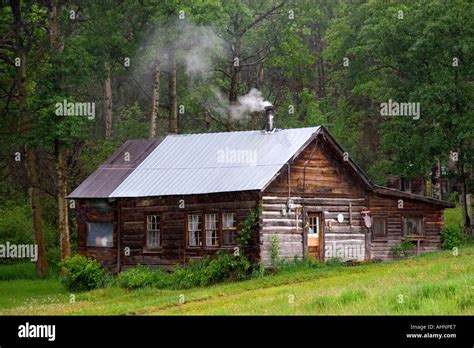Log Cabin With Smoke Coming Out Of Chimney In The Mountains Of British