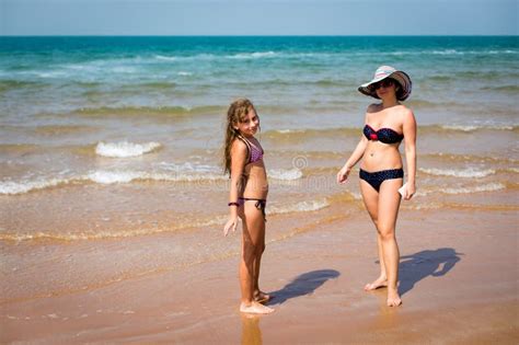 Garbnikującej Kobiety I Dziewczyny Pozycja Na Plaży Zdjęcie Stock