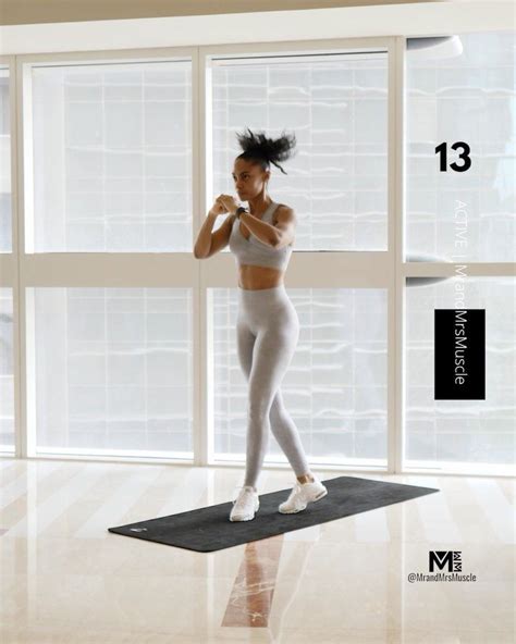 A Woman Is Standing On A Yoga Mat In The Middle Of A Room With Large Windows