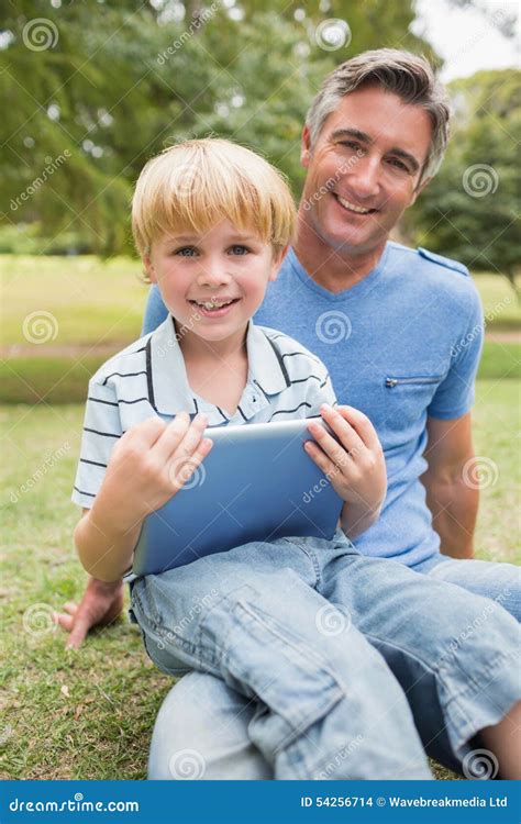Padre Feliz Con Su Hijo Que Usa La Tableta En El Parque Foto De Archivo