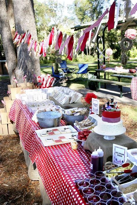 An Outdoor Picnic Area With Red And White Checkered Table Cloths Food