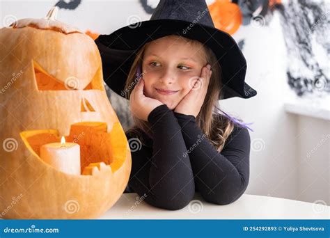 Cute Girl In Costume Of Witch With Pumpkin At Home Having Fun Celebrating Halloween Stock