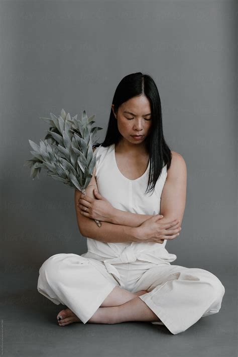 Woman Sitting Cross Legged In All White Crossing Her Arms Holding Pale