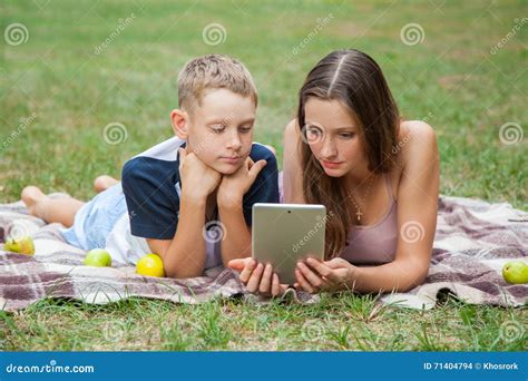 Young Sister And Brother Lying Down And Work With Tablet Stock Photo