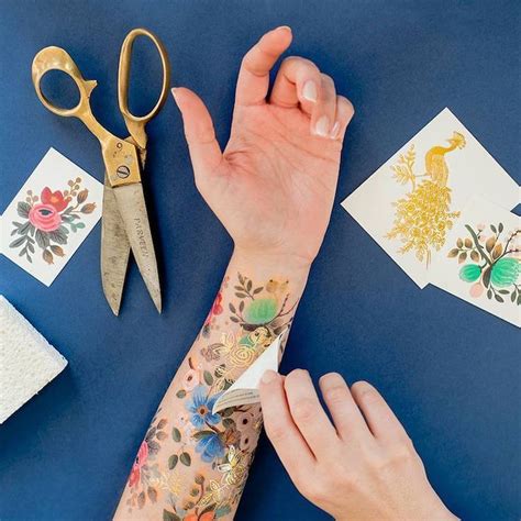 A Womans Arm With Tattoos And Scissors On It Next To Some Cards