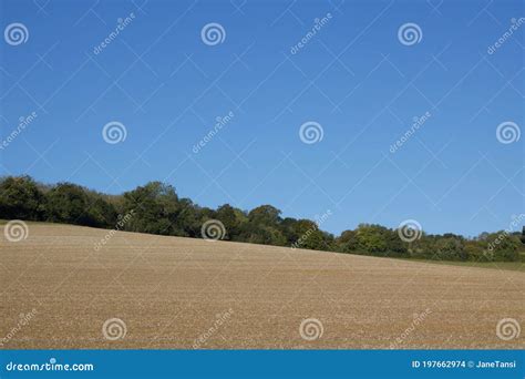 Rolling English Countryside With Field In Foreground And Deep Blue Sky