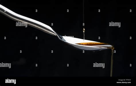 Close Up Of Honey Dripping From Spoon Against Black Background Stock Photo Alamy