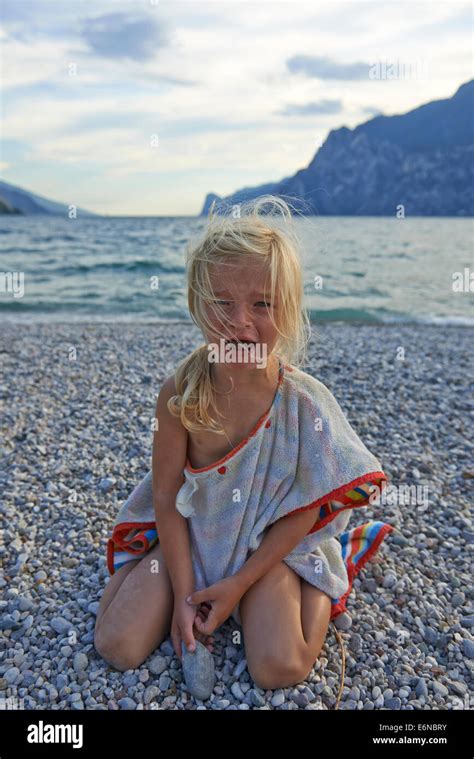 Portrait Of Child Blond Girl Crying At Pebbles Beach Background Stock