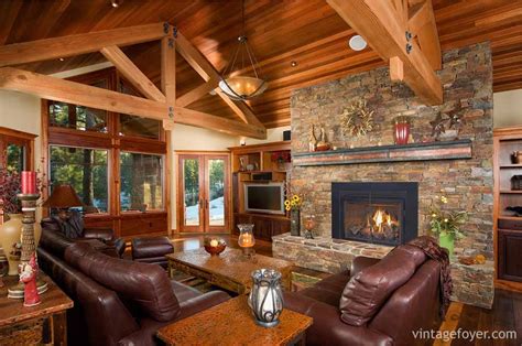 Multiple wooden elements tie the room together, including the coffee table, a pair of leather chairs with wooden frames, the ceiling, and a tower of logs stored in a cozy nook in the wall next to the fireplace. 44 Cozy Living Rooms & Cabins with Beautiful Stone Fireplaces