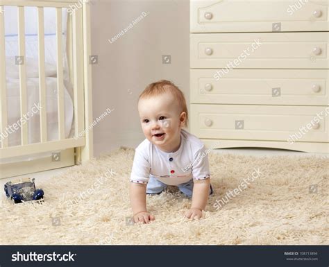 Little Child Baby Boy Sitting On The Floor On The Carpet Indoors In