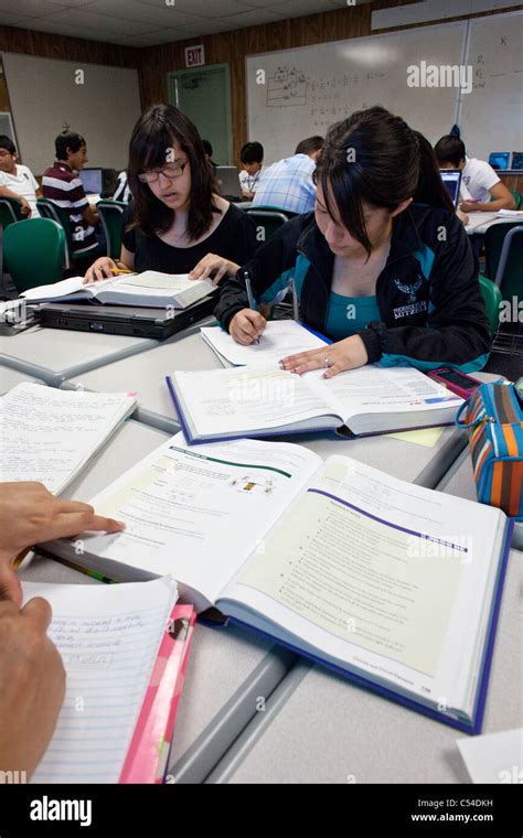 Students Use Textbooks On Desks To Write Reports On Notebooks Inside