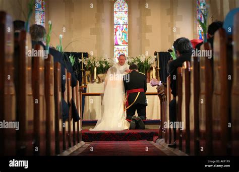 Bride And Groom Kneel At Altar During Typical Catholic Wedding Stock