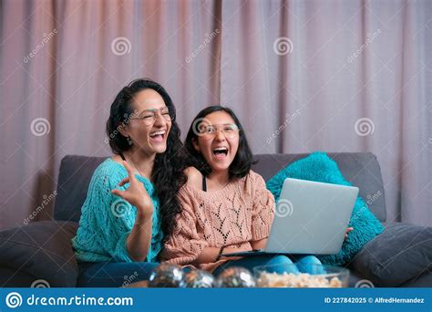 mom and daughter watching a laptop sitting on the sofa at home the two make expressions when