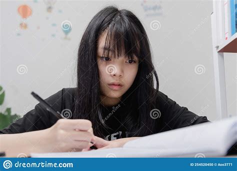 Asian Student Girl Is Writing Homework And Reading Book At Desk Stock