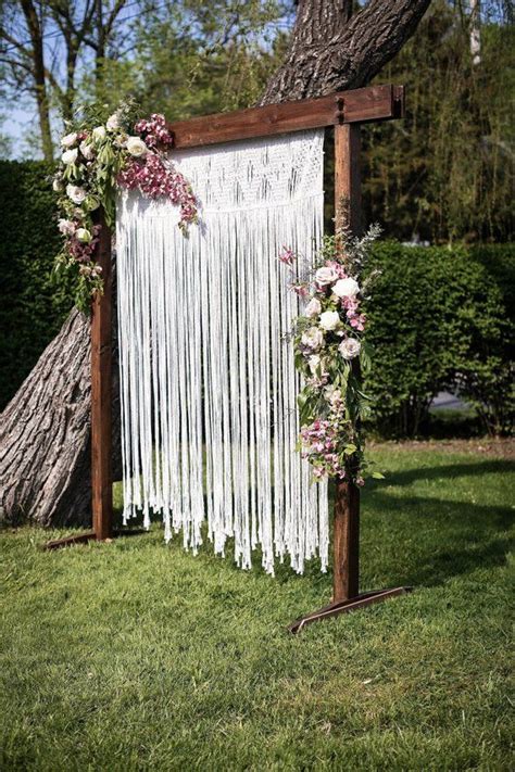 An Outdoor Wedding Ceremony With White Draping And Flowers On The Back