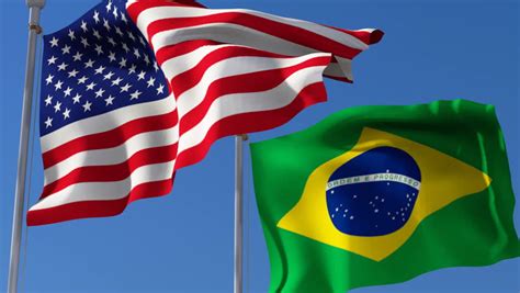 Flag Of Usa And Brazil Waving In The Wind Against Blue Sky Three