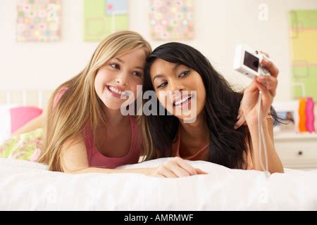 Two Girl Friends Taking Pictures Of Each Other As They Pose Beside The