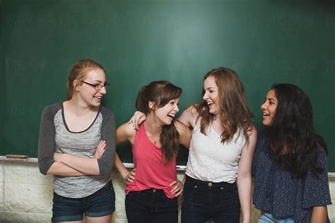 Group High School Girls Laughing In Front Of Green Chalkboard By