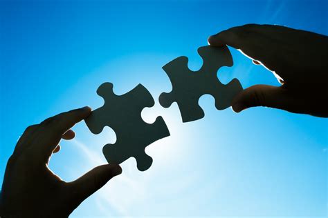 Hands Connecting Two Puzzle Pieces Knowledge Capital Group