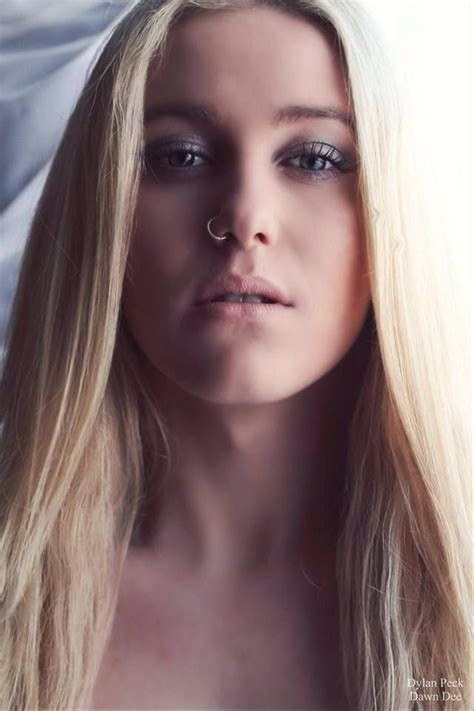 a woman with long blonde hair and piercings on her nose looking at the camera