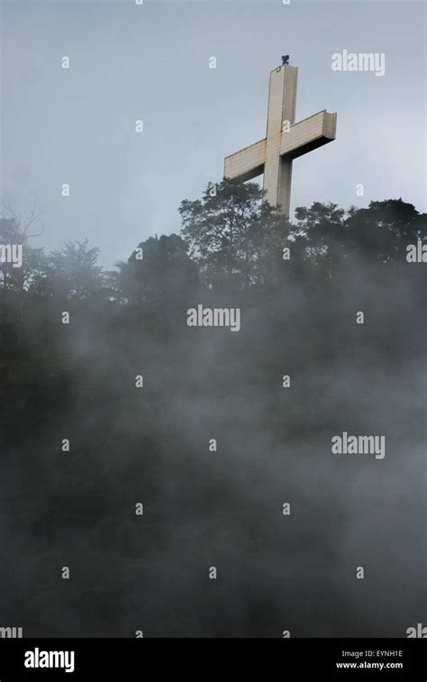 A Tall Christian Cross Is Seen Through Fog On A Ridge At Bukit Kasih A