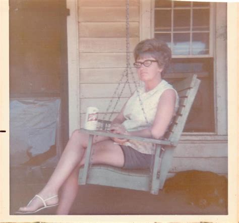 An Old Photo Of A Woman Sitting On A Porch Swing Holding A Cup And
