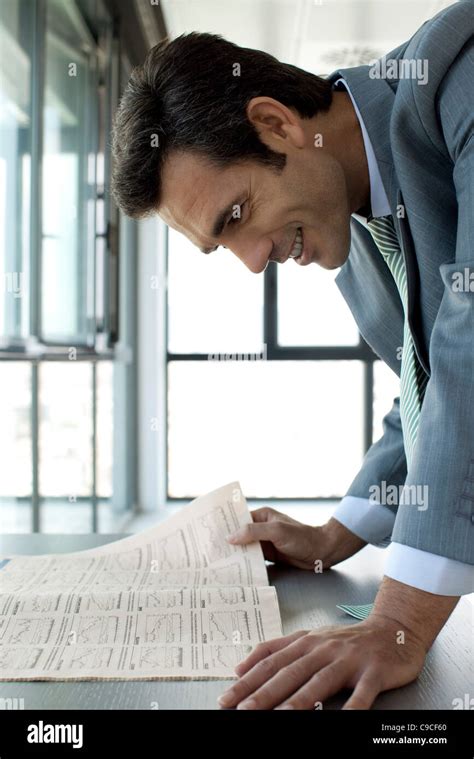 Businessman Reading Finance Section Of Newspaper Smiling Stock Photo