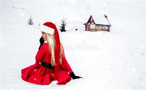 merry christmas beautiful blonde woman in red dress and santa clause hat on a background of