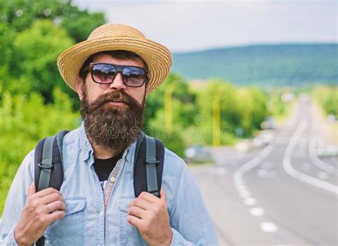 tips of experienced traveler man bearded hipster backpacker at edge of highway take me with