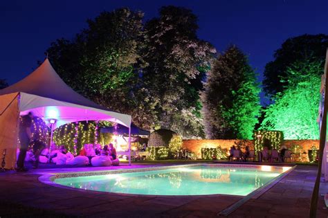 An Outdoor Swimming Pool Surrounded By Trees At Night
