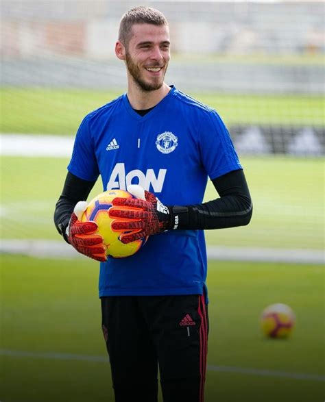 A Man Holding A Soccer Ball In His Hands On A Field With Other Balls Behind Him