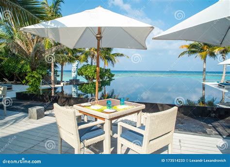 Dining Setup Chairs And Table Under Umbrella Near Swimming Pool At The