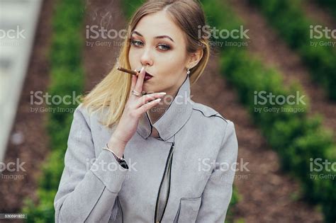Young Woman Smoking Cigarette On The Bench Stock Photo Download Image