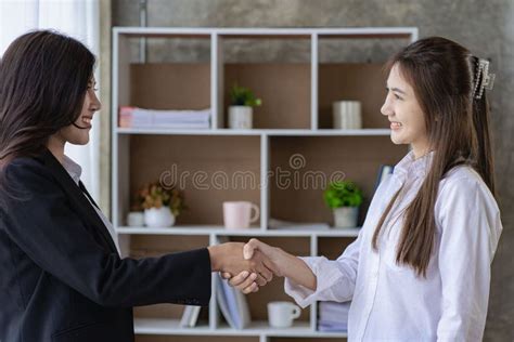 Two Young Asian Business Women Shake Hands With Their Coworkers In A