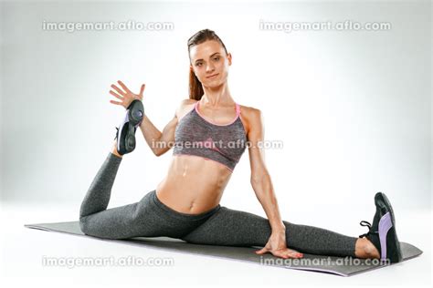 Beautiful slim brunette doing some stretching exercises in a gymの写真素材