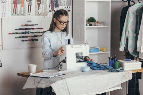 Female Fashion Designer Using Sewing Machine At Design Studio Stock Photo