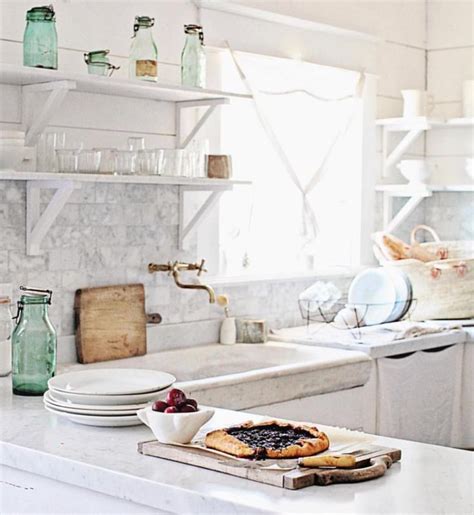 A Kitchen With White Counter Tops And Open Shelves