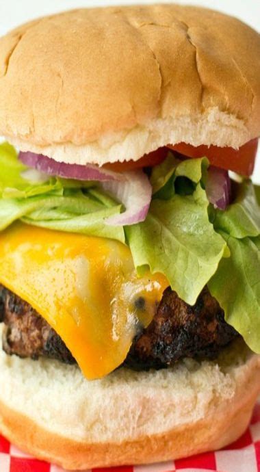 A Cheeseburger With Lettuce And Onions On A Checkered Tablecloth