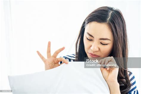 Beautiful Woman Sniffing A White Pillow With A Foul Odor Or Musty Smell