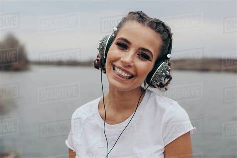 Portrait Of A Smiling Woman Wearing Spiked Headphones Stock Photo