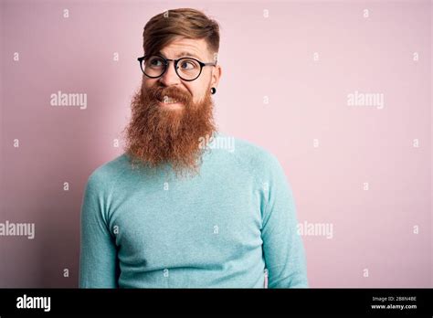 Handsome Irish Redhead Man With Beard Wearing Glasses Over Pink
