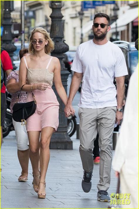 A Man And Woman Are Walking Down The Street Holding Hands Both Dressed