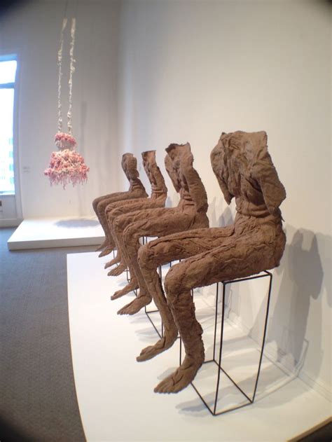 Three Wooden Sculptures Sitting On Top Of A Metal Stand In Front Of A